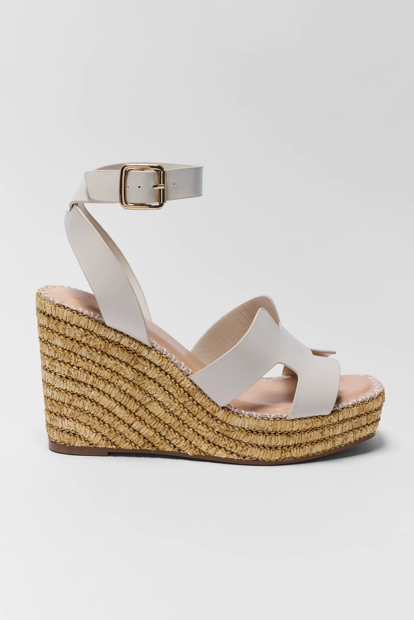 White wedge sandal with a textured sole on a light gray background
