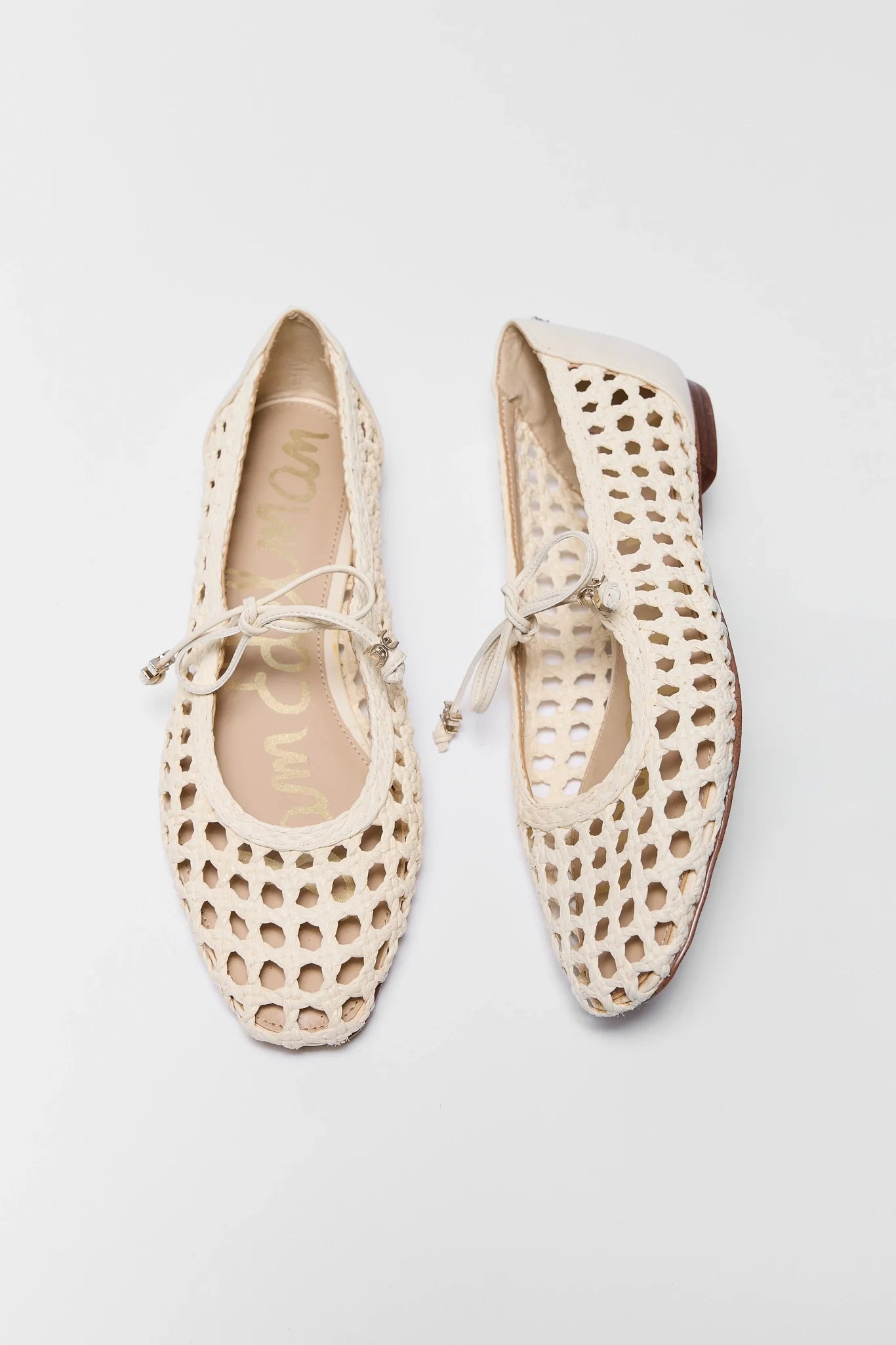 Pair of beige perforated flat shoes on a light gray background