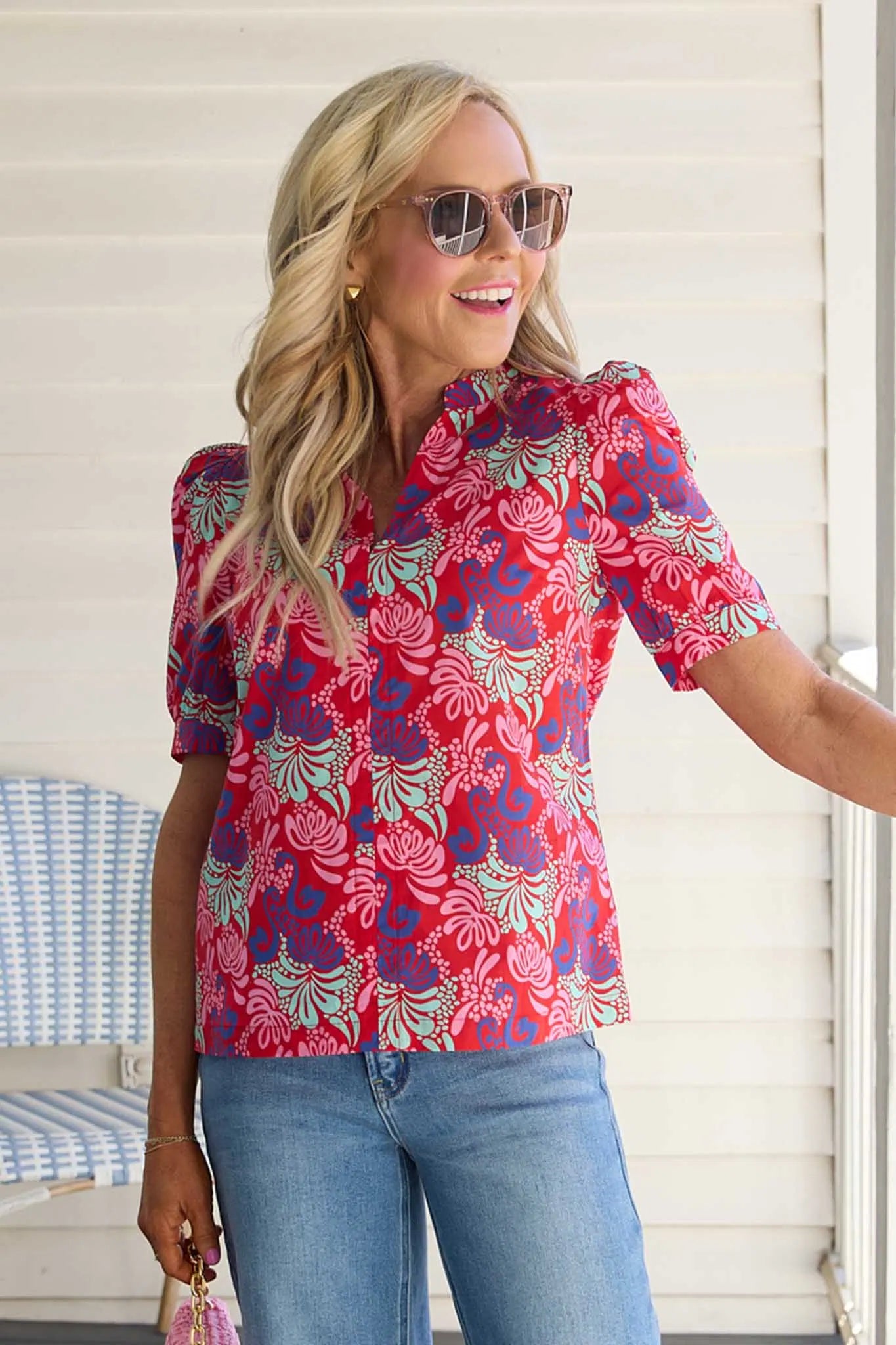 Woman wearing a colorful floral blouse and sunglasses outdoors.