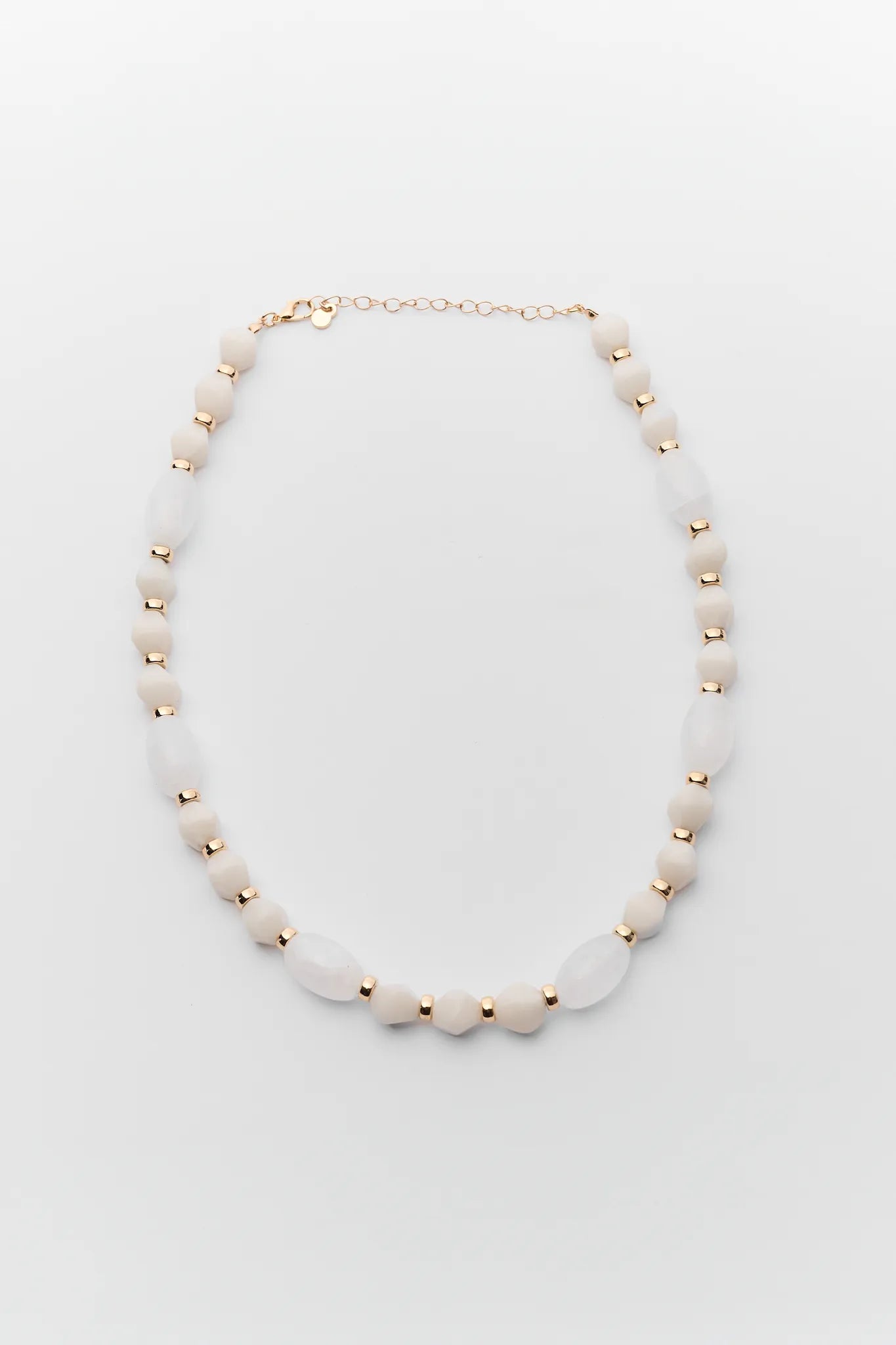 Necklace with white beads and gold accents on a light gray background