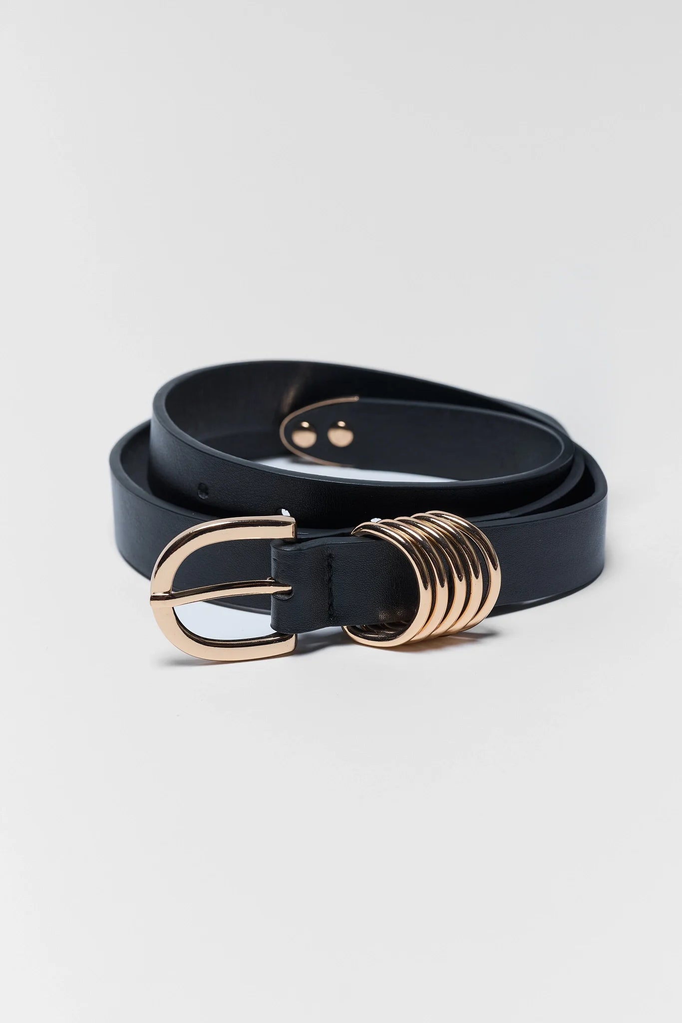 A black leather belt with a gold-tone buckle and a distinctive multi-ring decorative detail on the side, displayed on a light gray background.