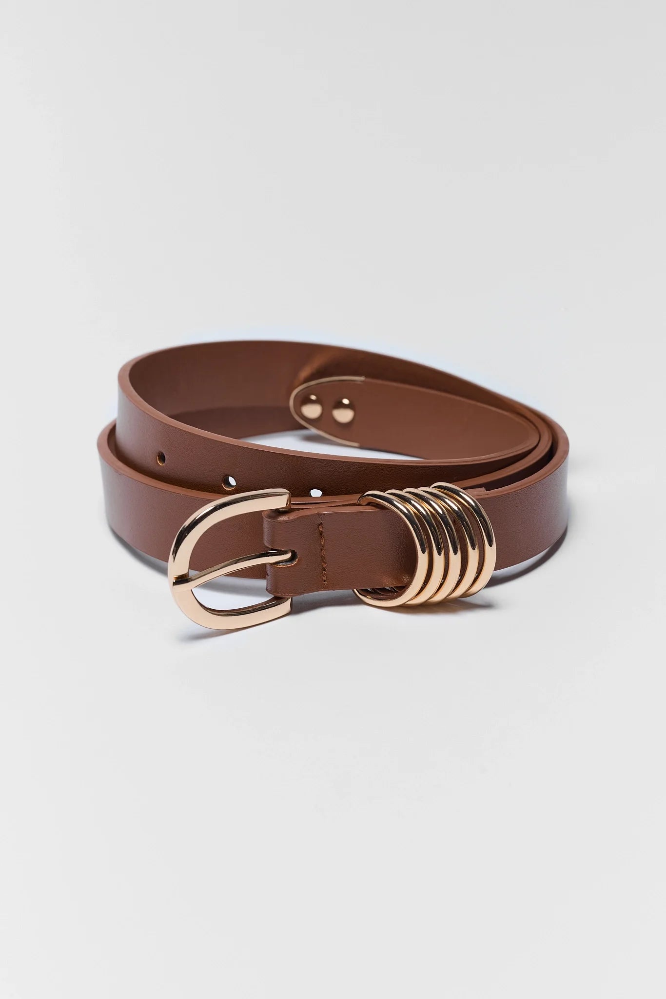 A brown leather belt with a polished gold-tone buckle and a distinctive multi-ring decorative detail on the side, displayed on a light gray background.