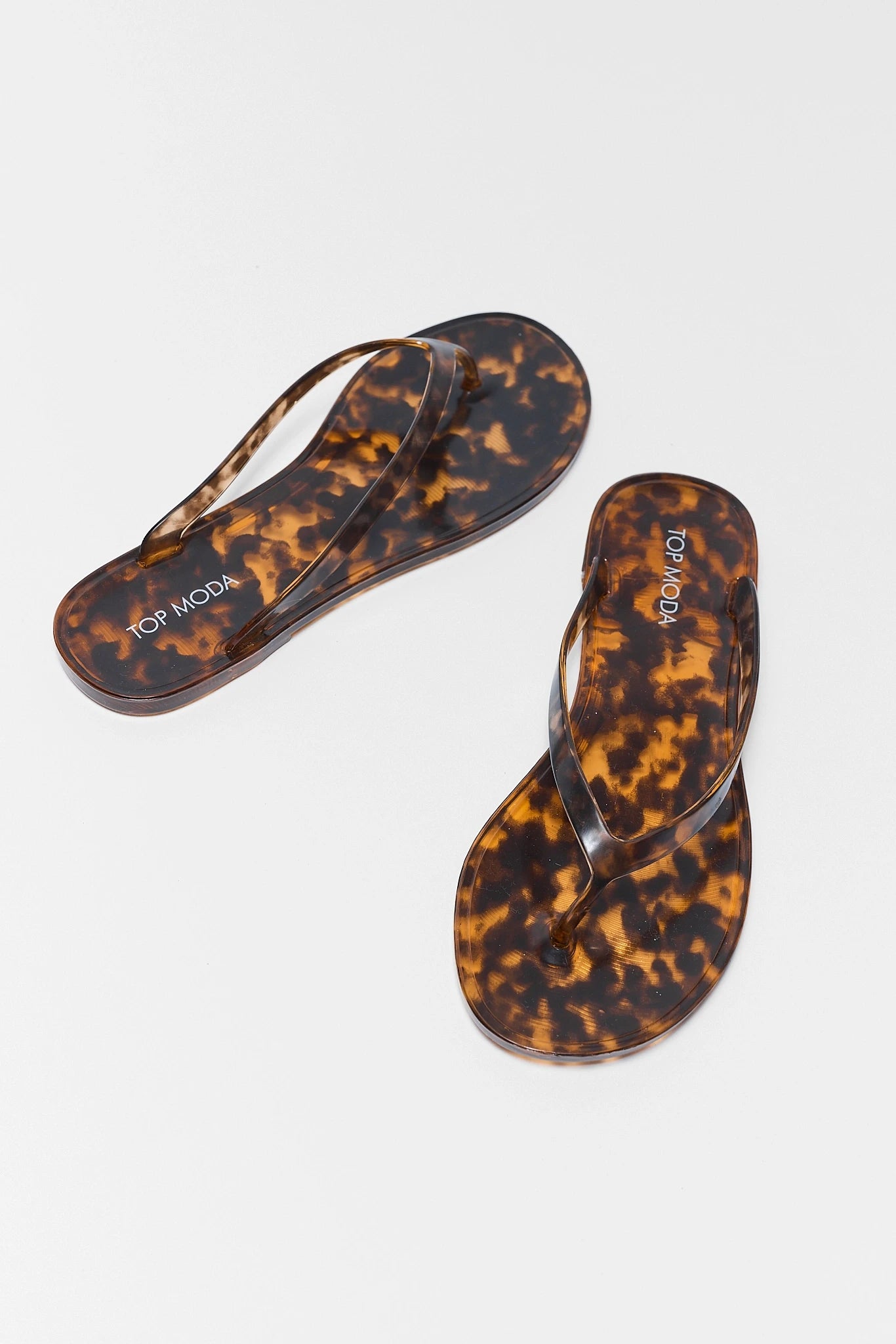 Tortoiseshell sandals with branding on a light gray background