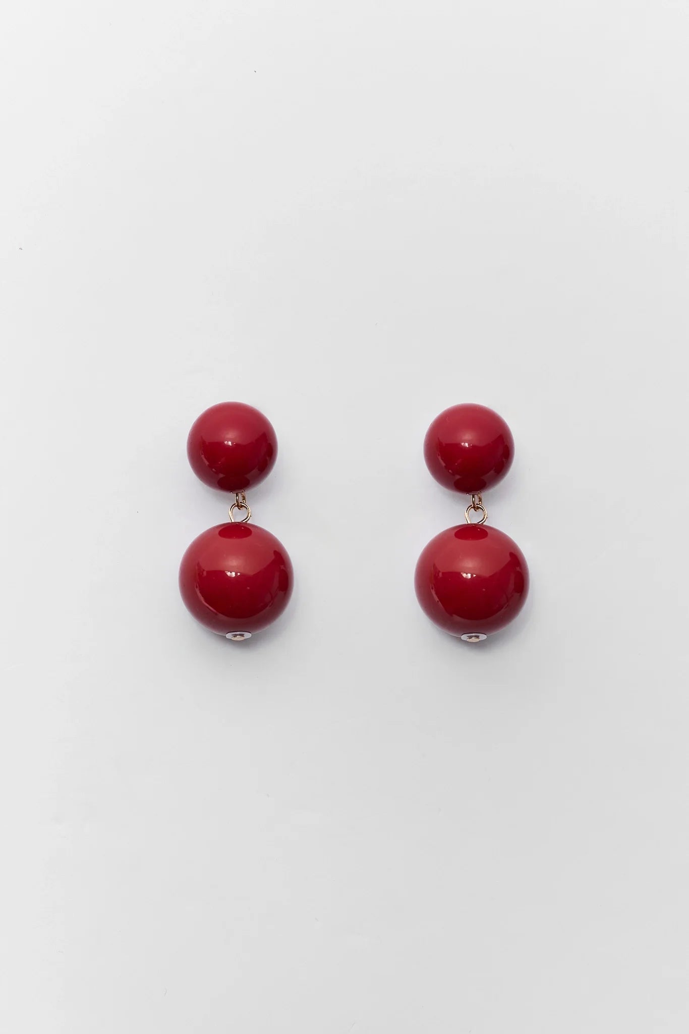 A pair of double-drop red beaded drop earrings with small gold-toned metal connectors, displayed on a clean white background.