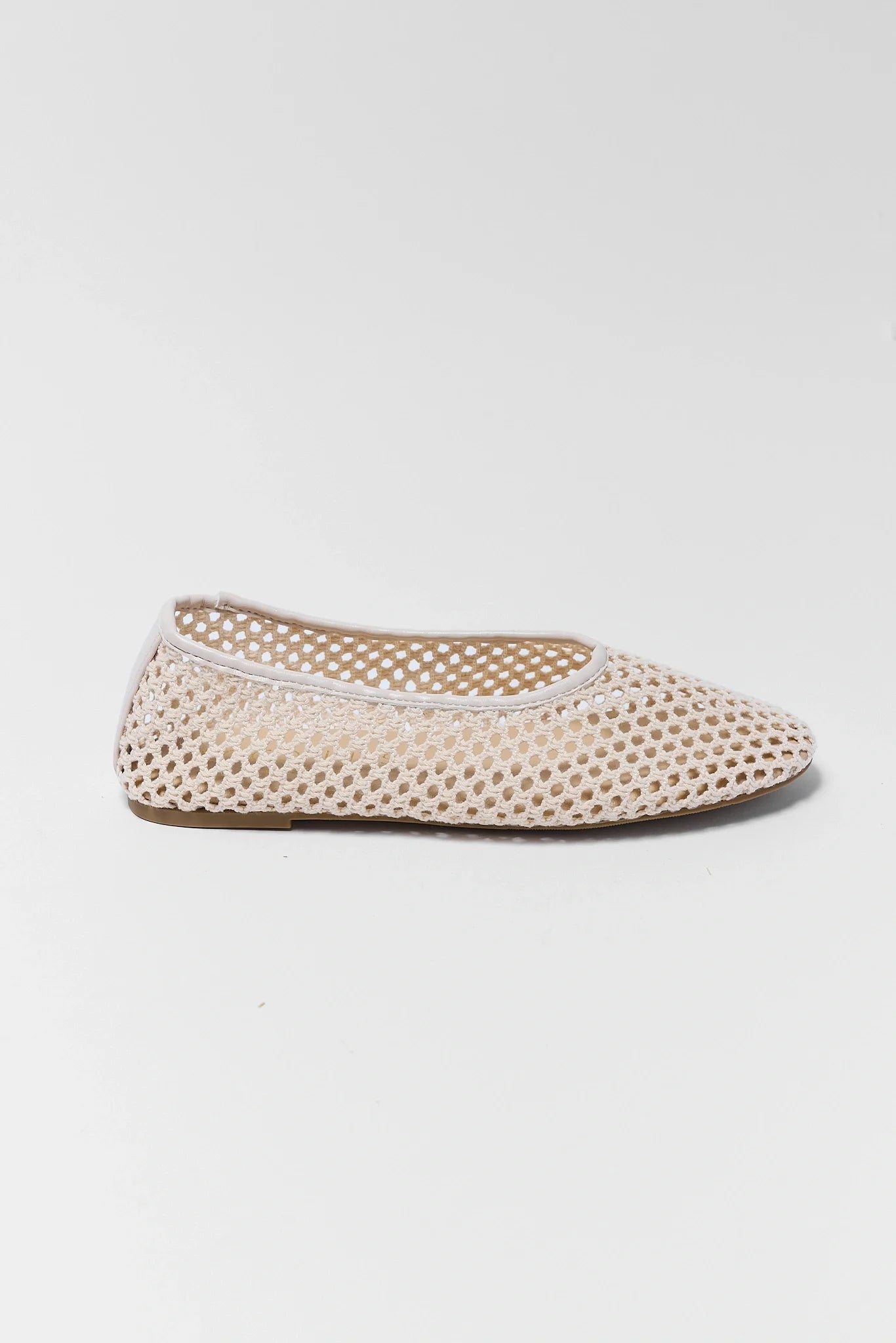 one Beige perforated flat shoe on a light gray background