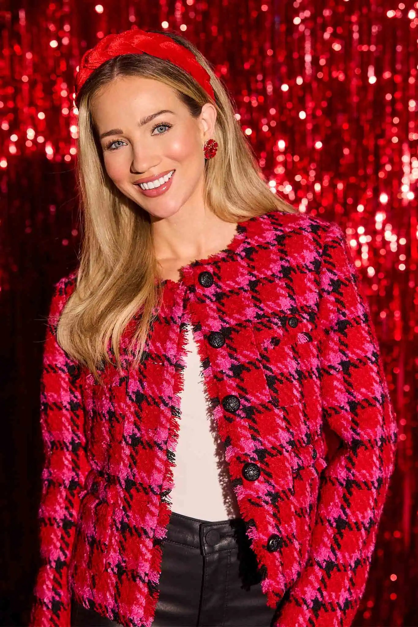 Woman wearing a red and black checkered maryl jacket with a sequined red background
