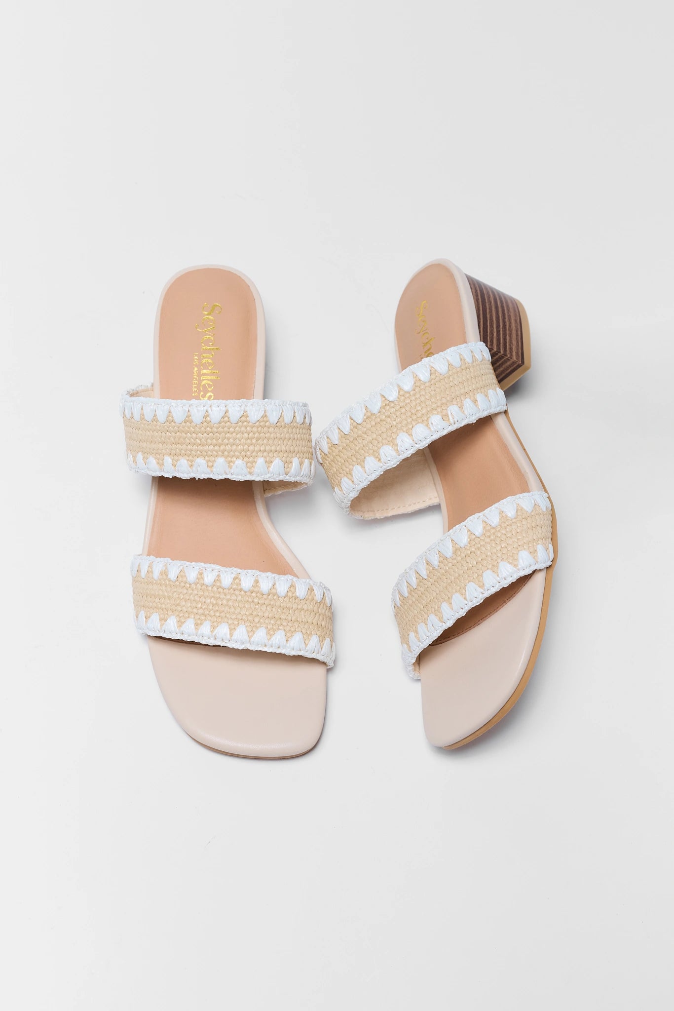 Pair of beige sandals with white straps on a light gray background