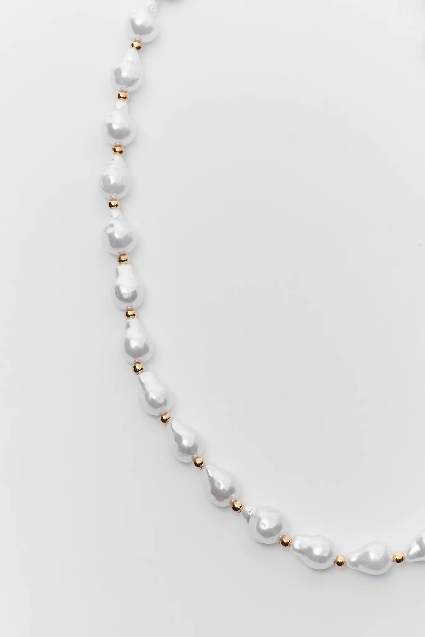 Pearl necklace with gold beads on a light gray background