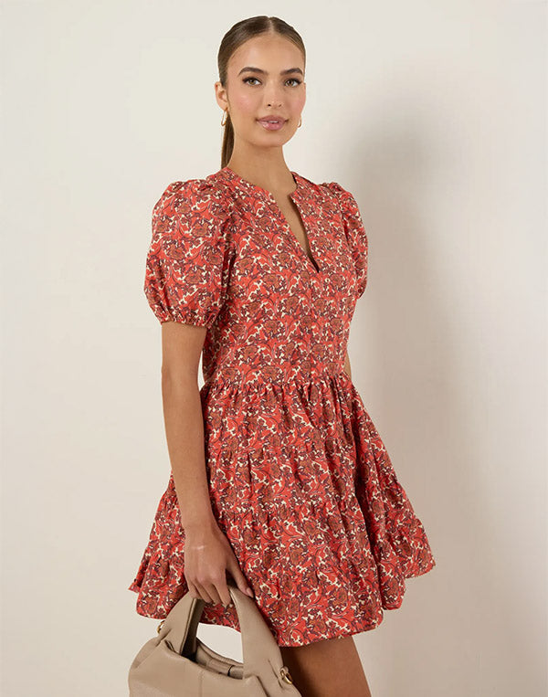 woman wearing orange floral dress on white background