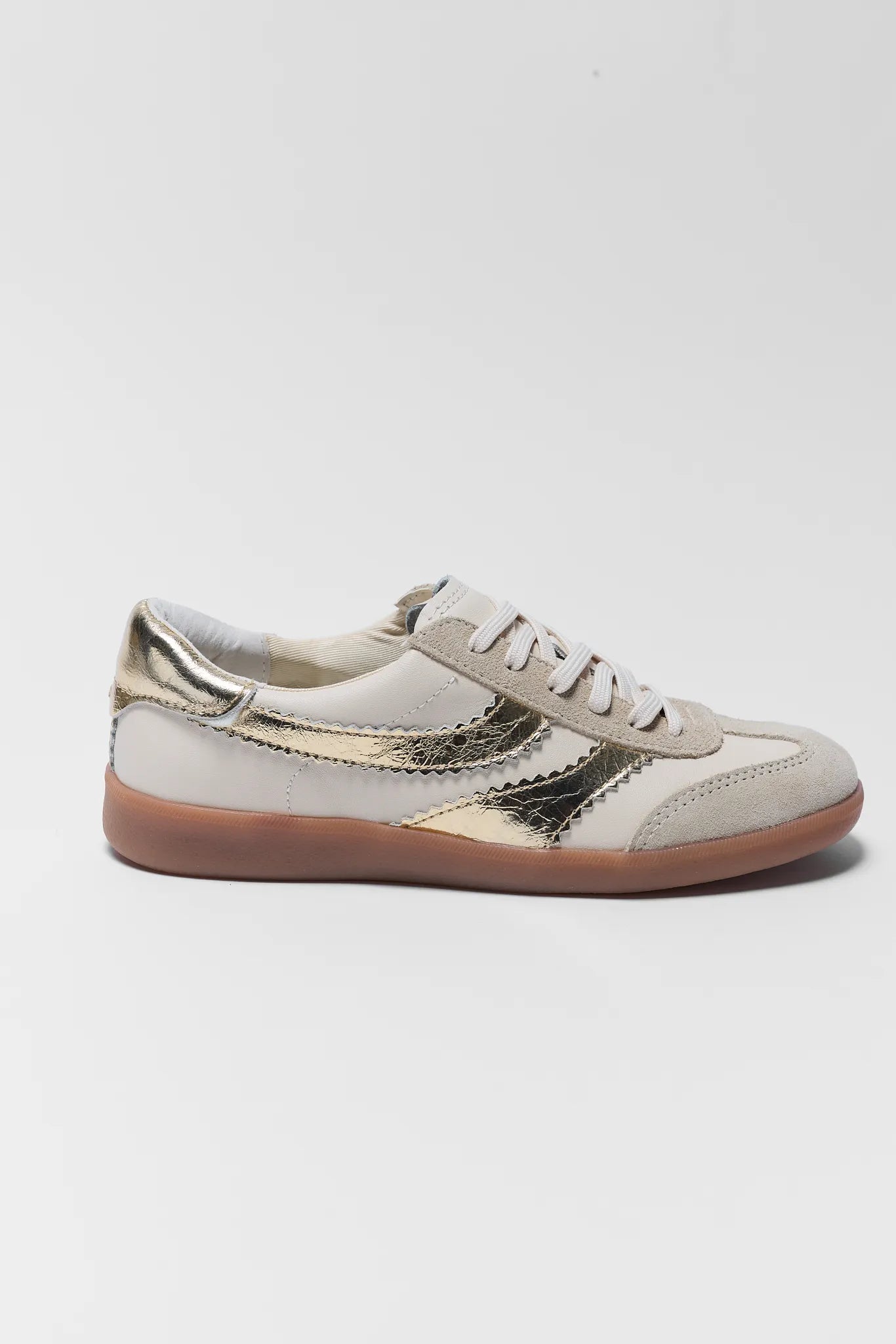 White sneaker with gold accents on a light gray background