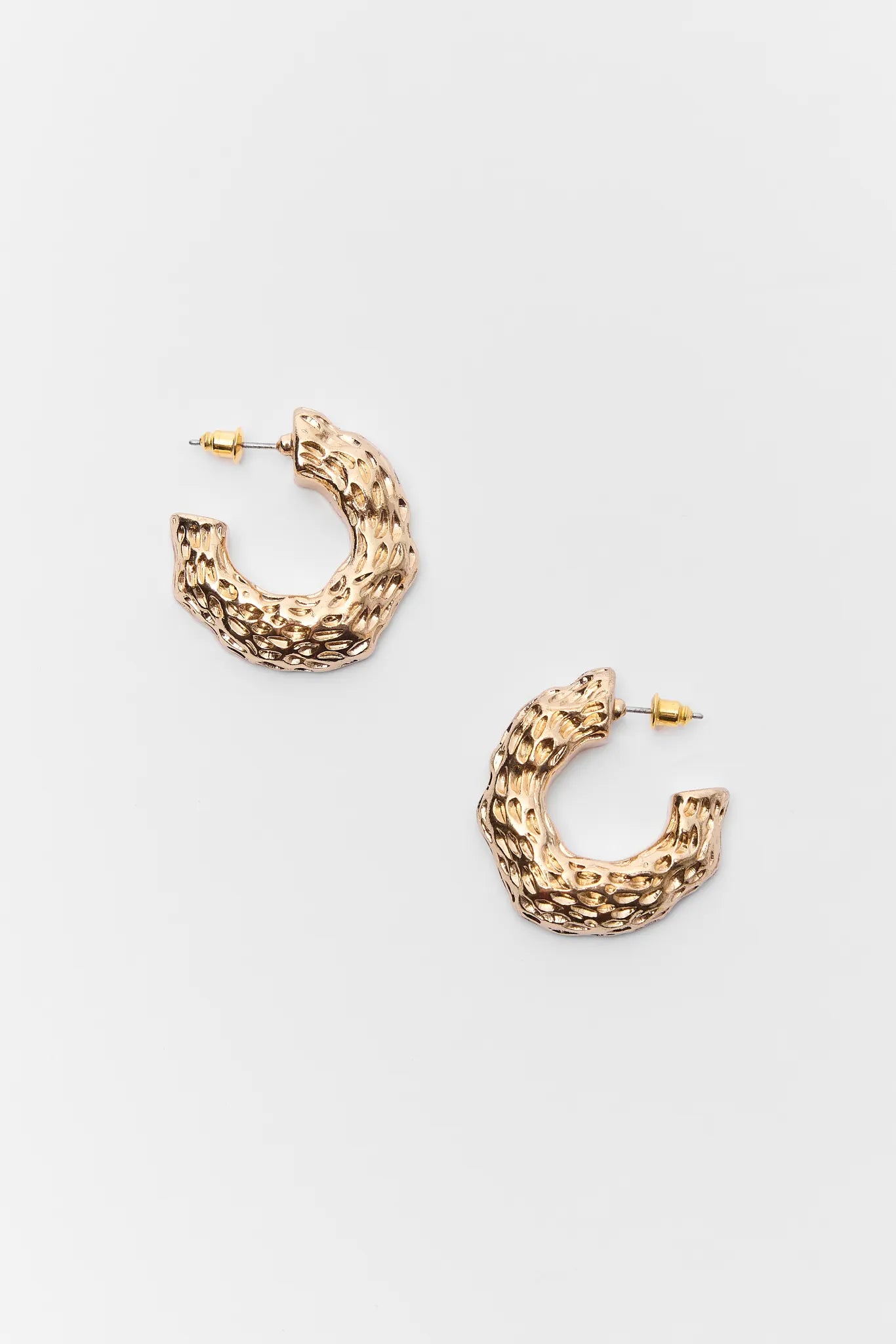 Gold hoop earrings on a light gray background