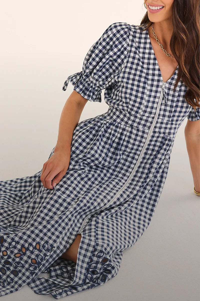 Woman wearing a blue and white checkered dress with floral details on a light background desktop