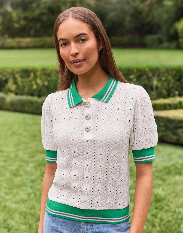Woman wearing a white and green patterned shirt with a garden background