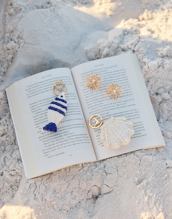 Three decorative brooches on an open book in sand nav