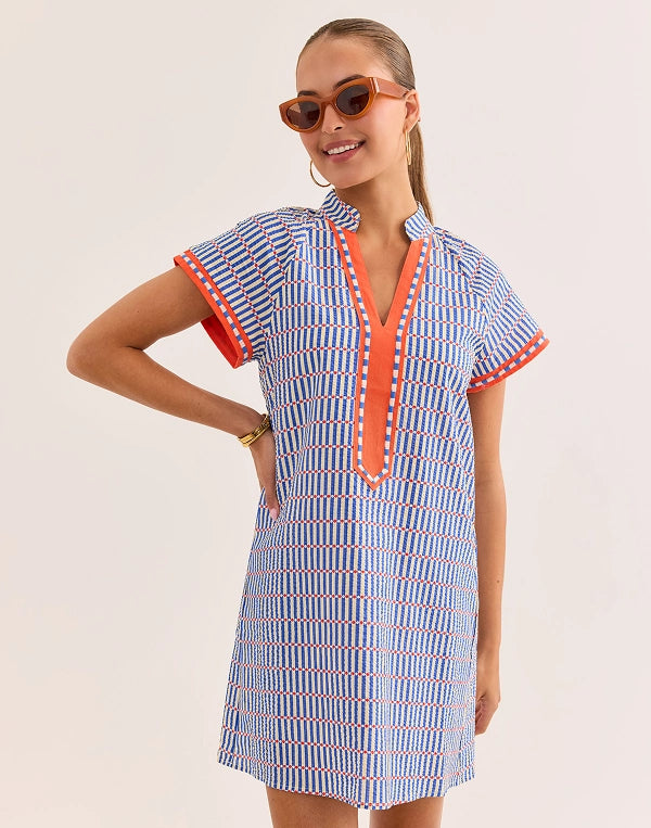 Woman wearing a blue and orange dress with sunglasses on a beige background navigation