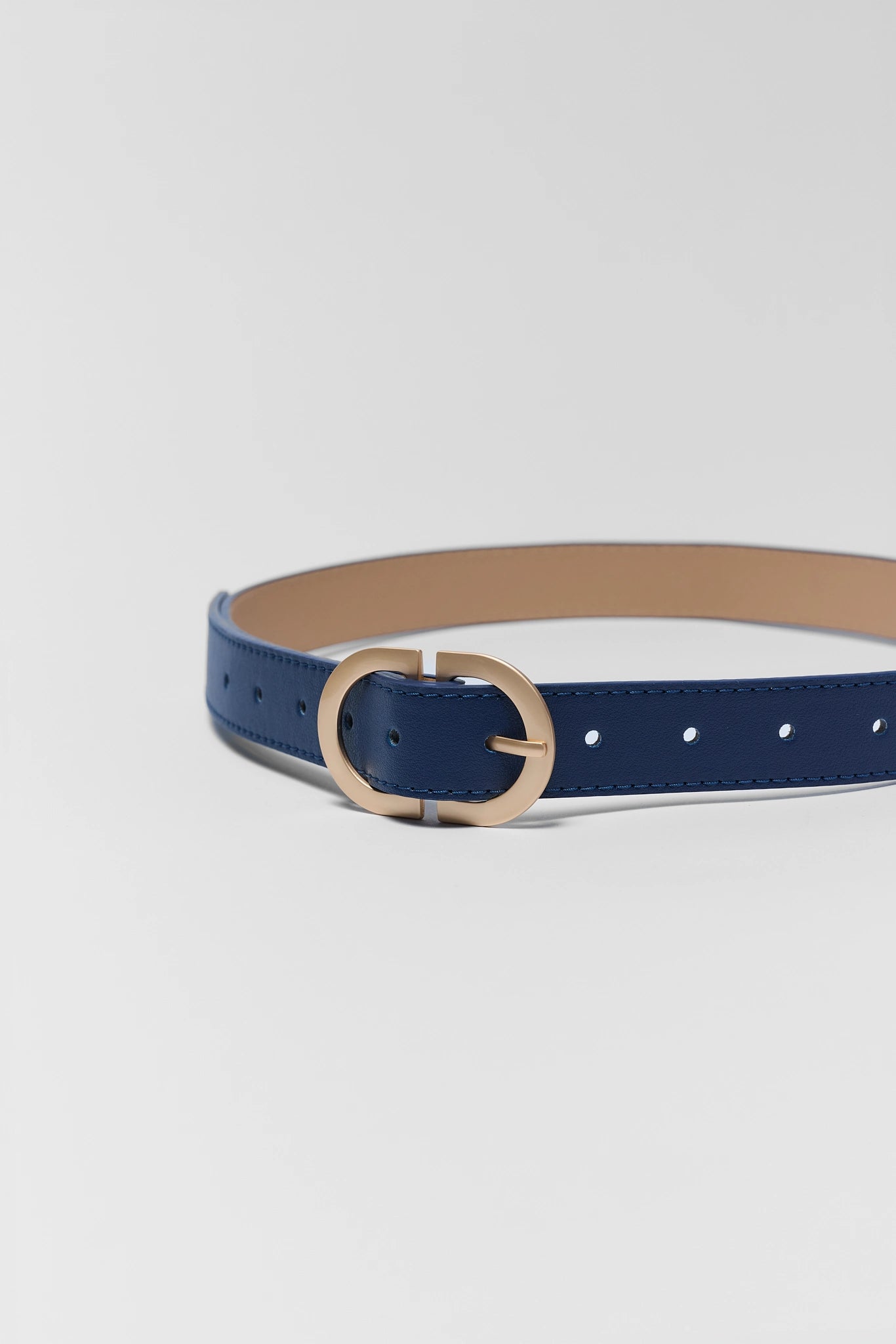 close up Navy blue belt with a gold buckle on a light gray background
