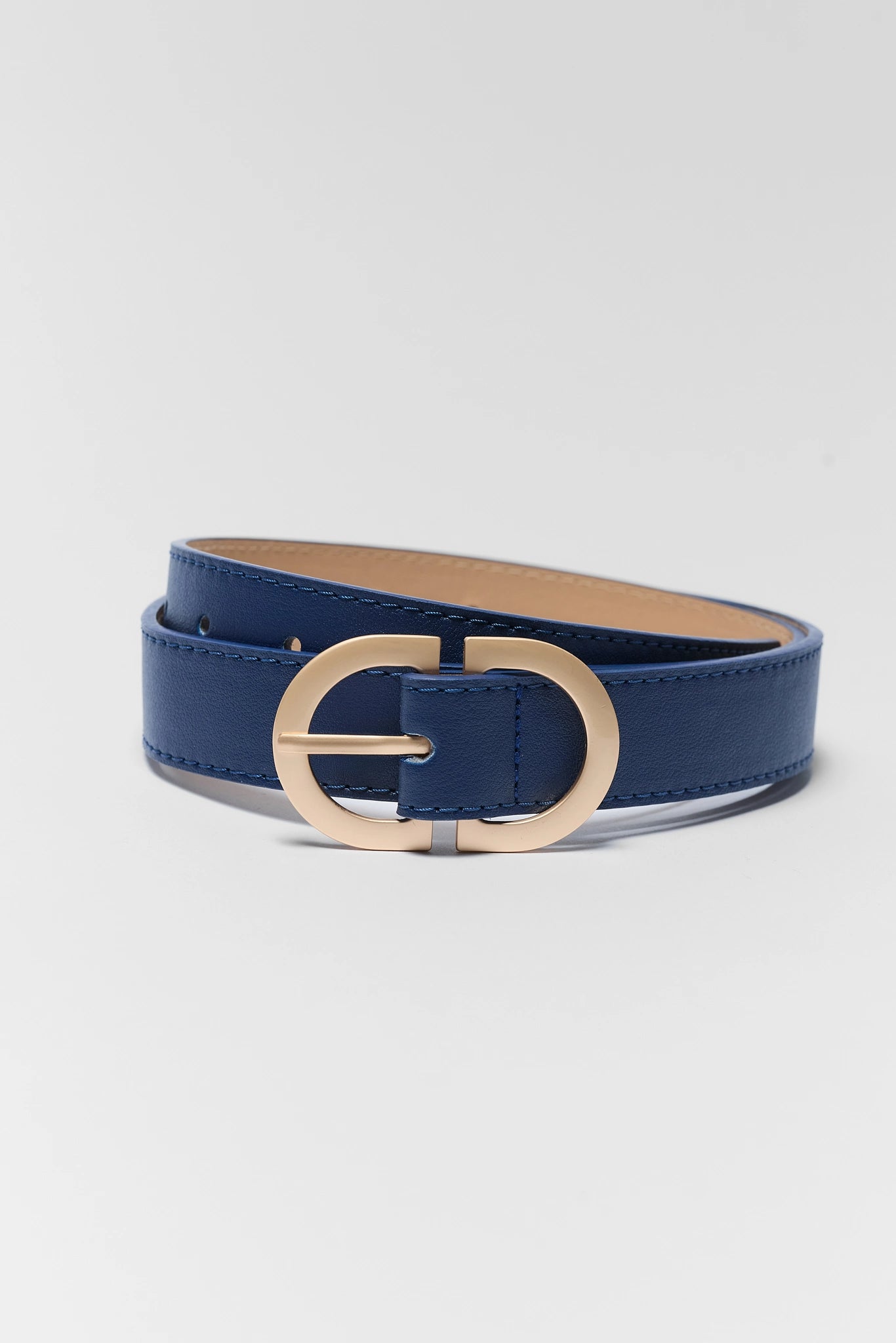 A blue leather belt with a large, polished gold-tone oval buckle, coiled on a light gray background.