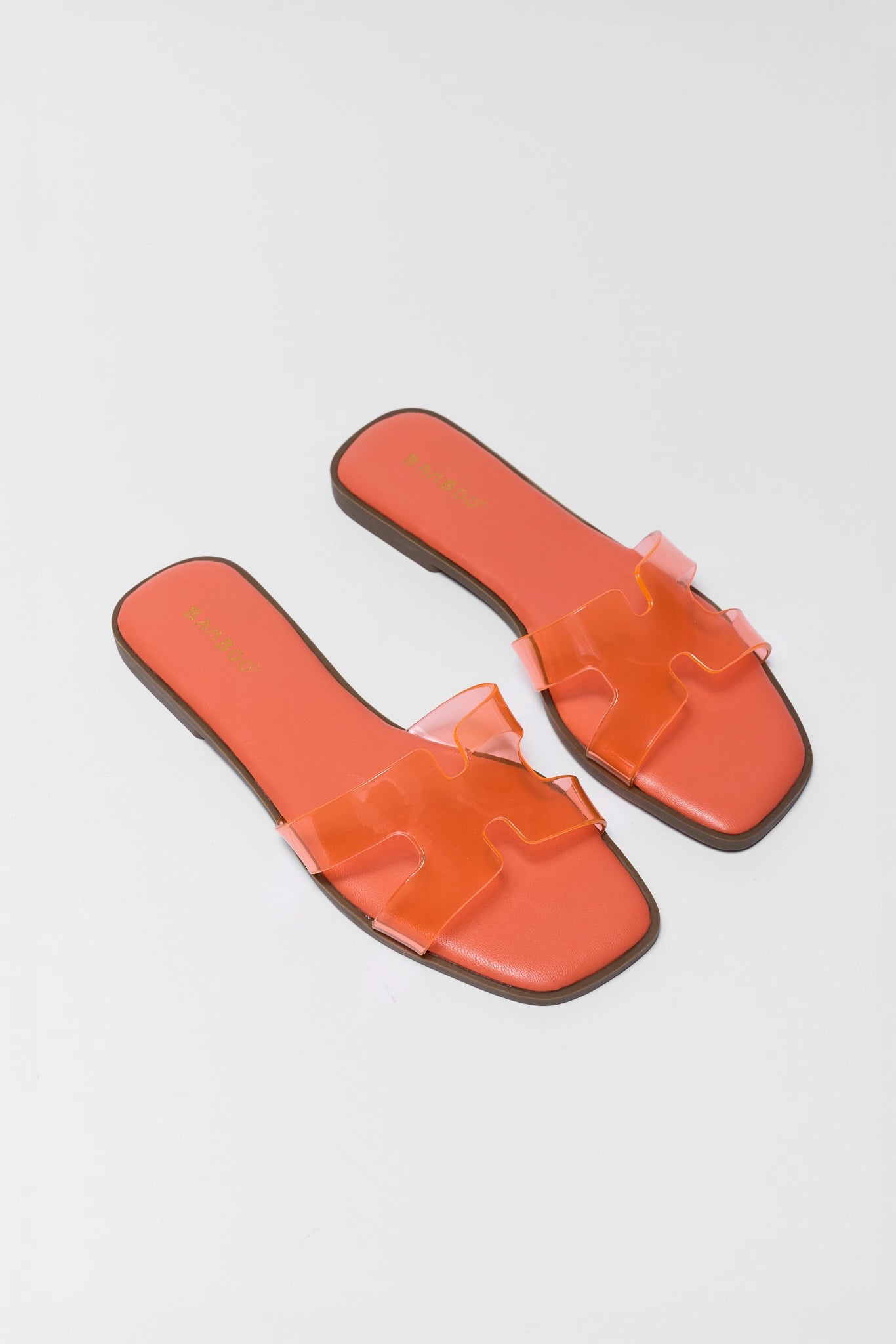Pair of two orange clear slide sandals on a light gray background