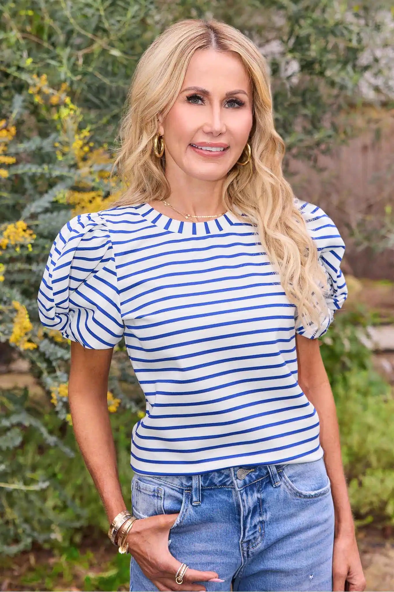 Woman wearing a blue and white striped shirt with puffed sleeves outdoors.