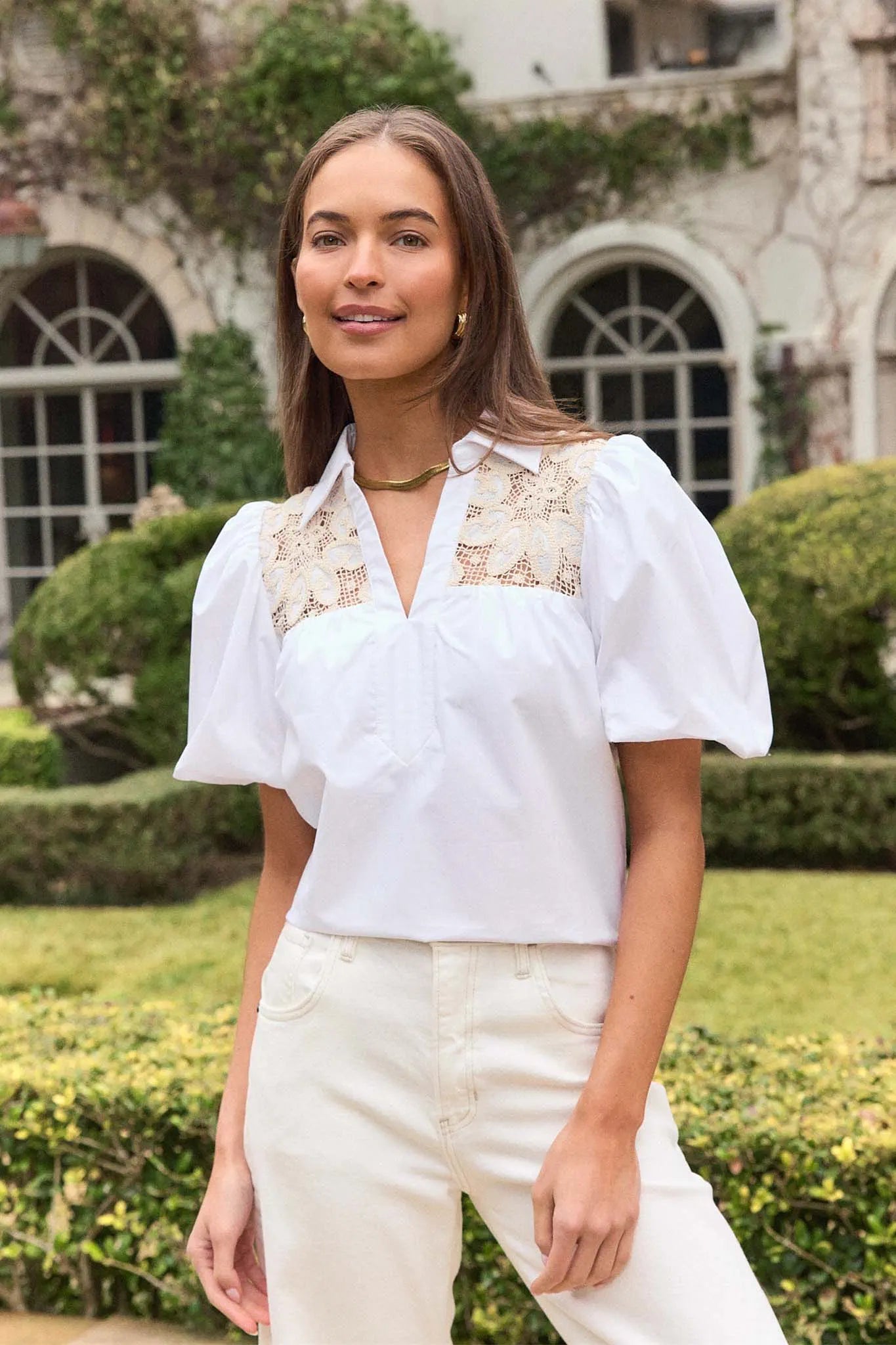 Woman wearing a white blouse with lace details in an outdoor setting