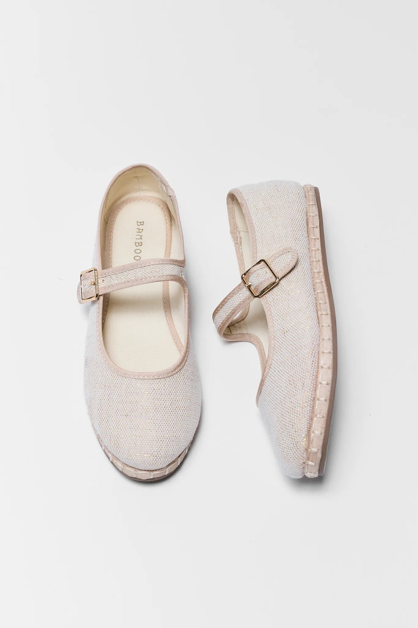 Pair of beige flat shoes with buckles on a light gray background
