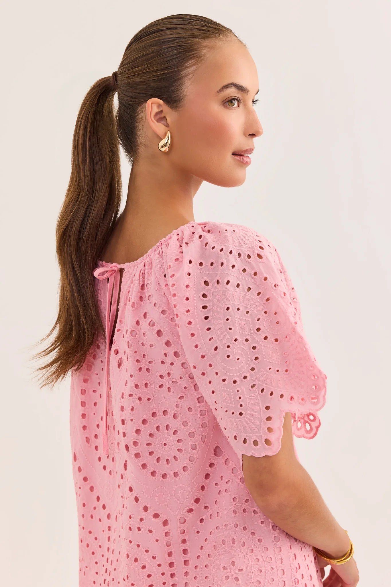 Woman wearing a pink dress with a white background close up