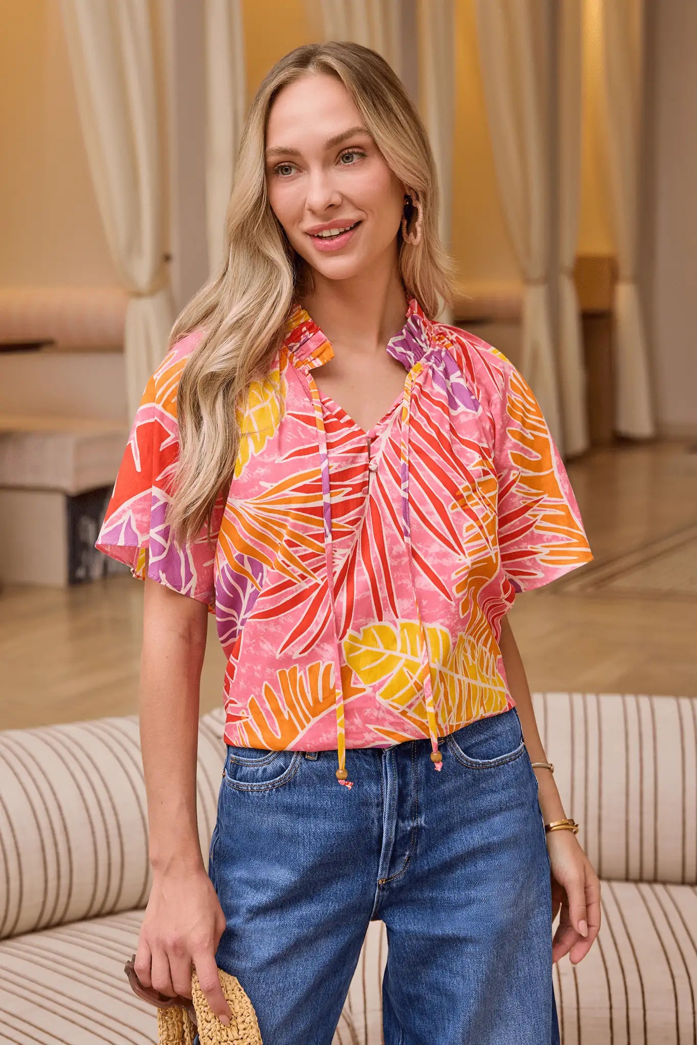 Woman wearing a colorful patterned shirt and blue jeans in an indoor setting. lifestyle