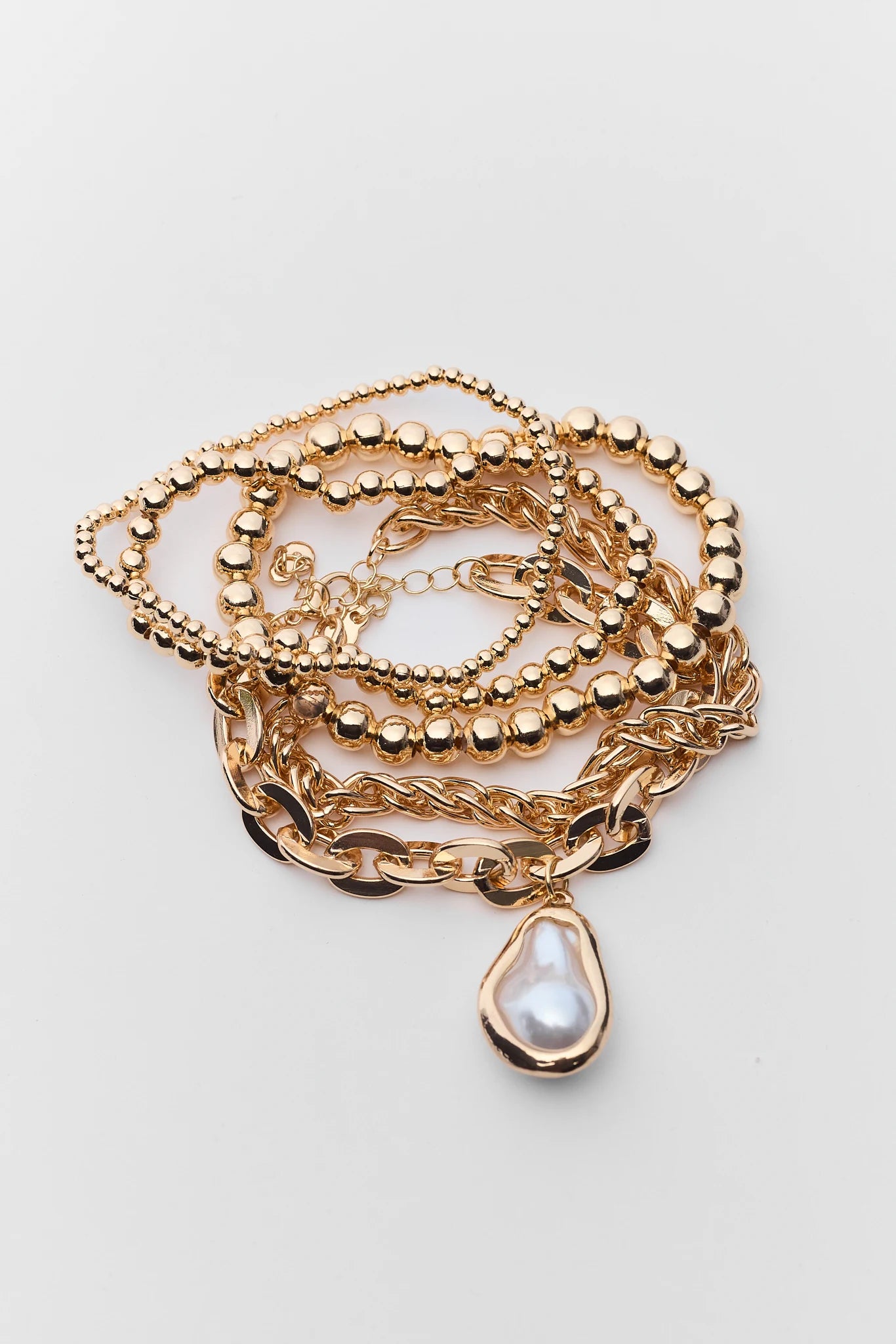 Gold necklace with a teardrop pendant on a light gray background