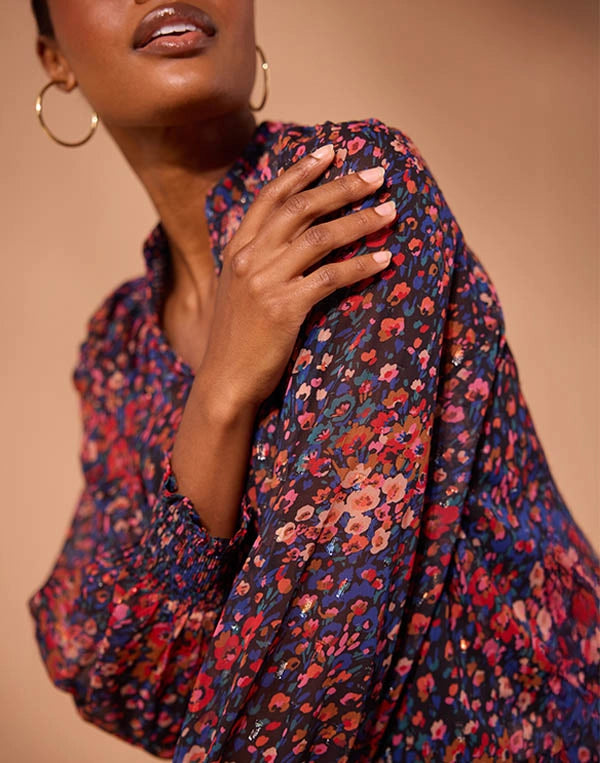 Woman wearing a floral patterned garment against a beige background