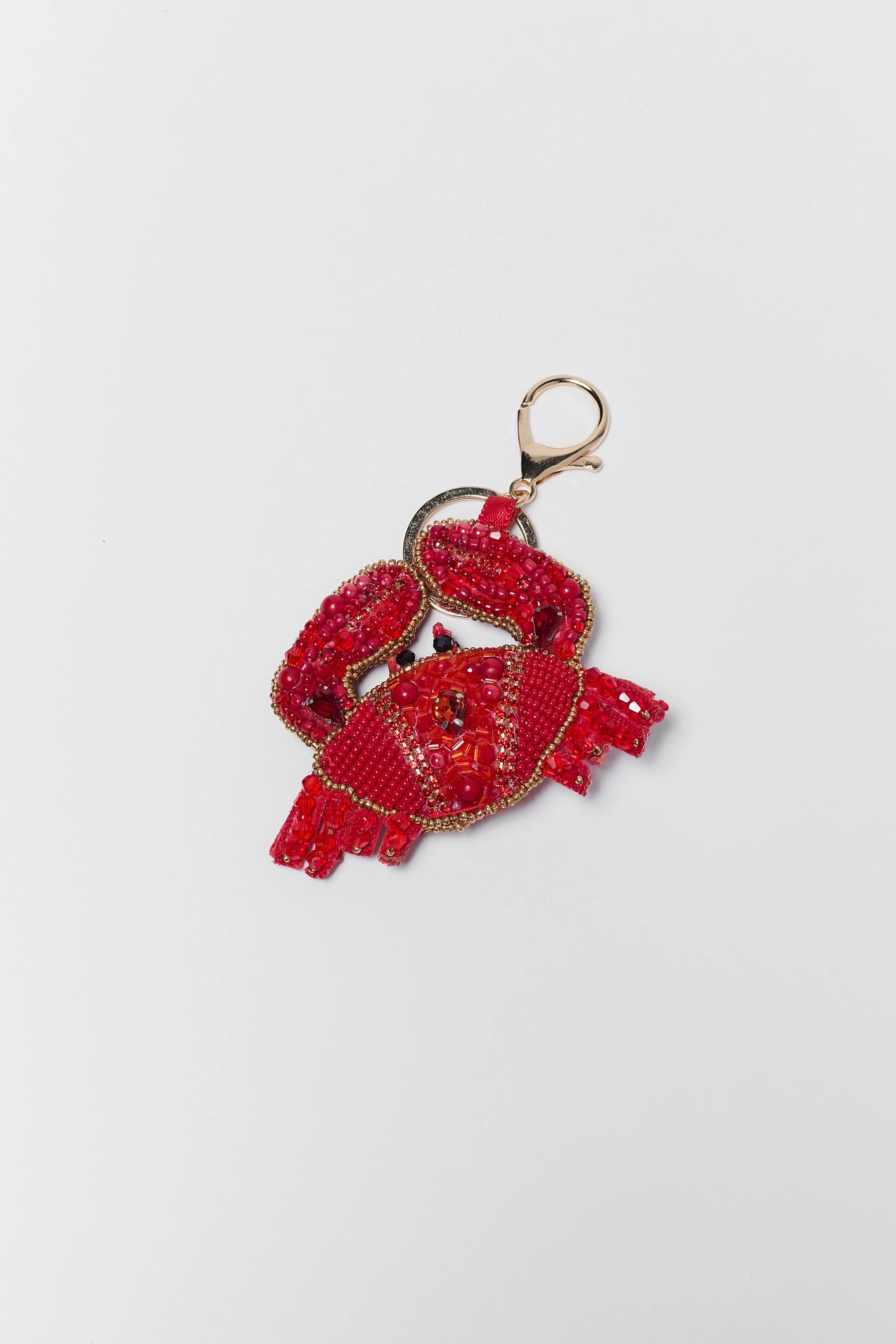 Red crab-shaped keychain with gold ring on a light gray background