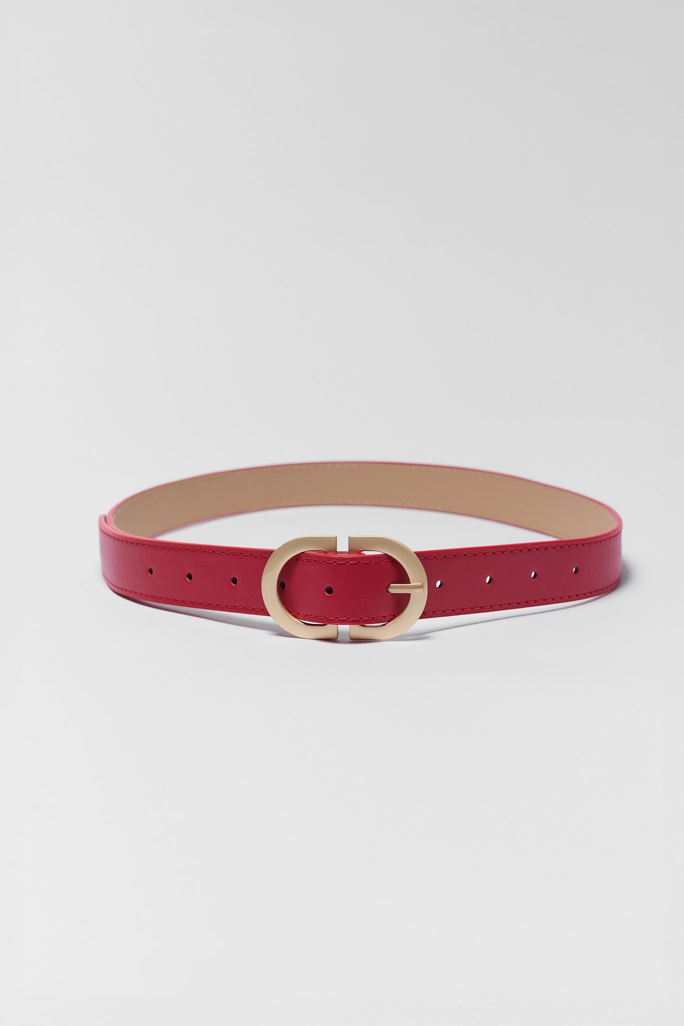 Red belt with a gold buckle on a light gray background