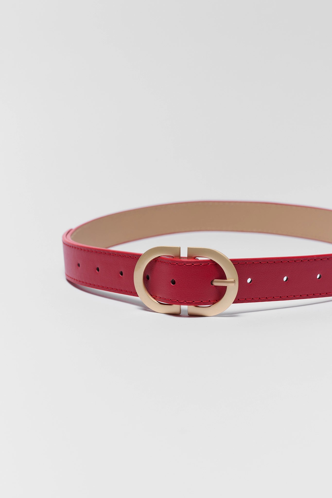 close up Red belt with a gold buckle on a light gray background