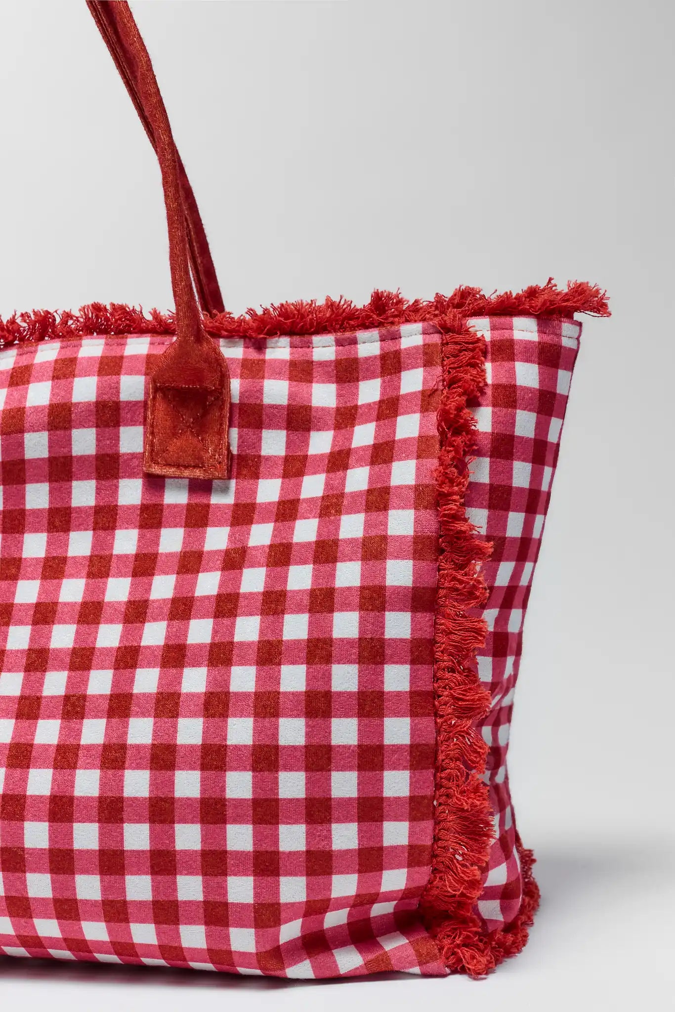 close up Red and white checkered bag with frayed edges on a light gray background