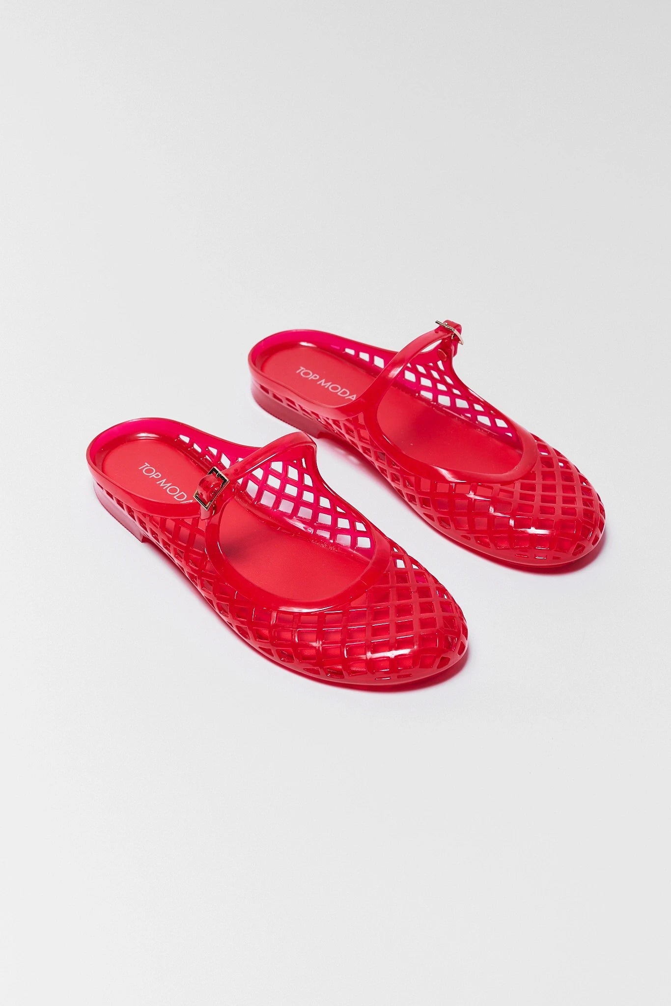 two Red jelly sandals on a white background