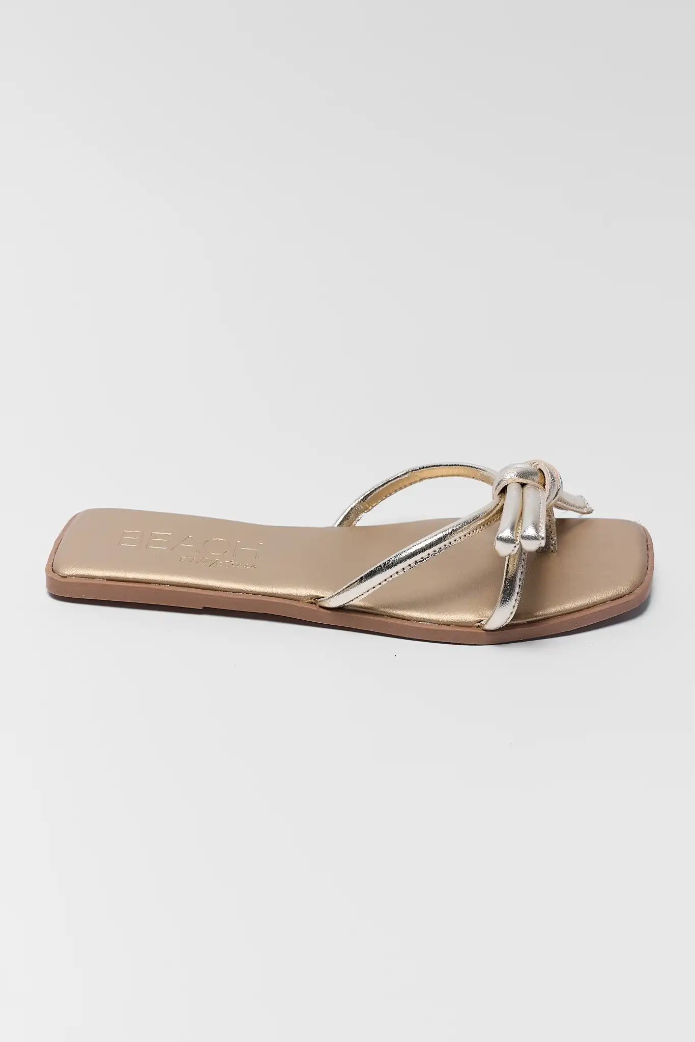 one Gold sandal with a bow on a white background