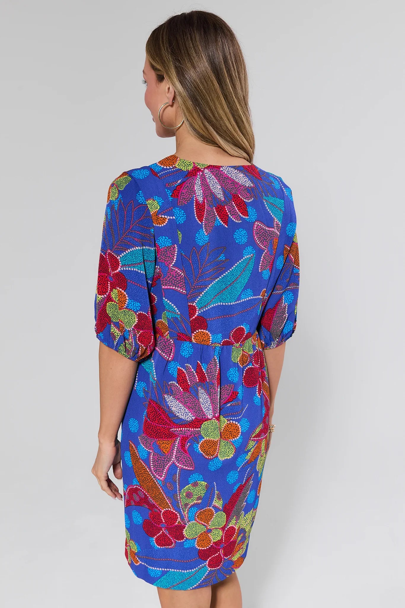 Woman wearing a colorful floral dress against a white background