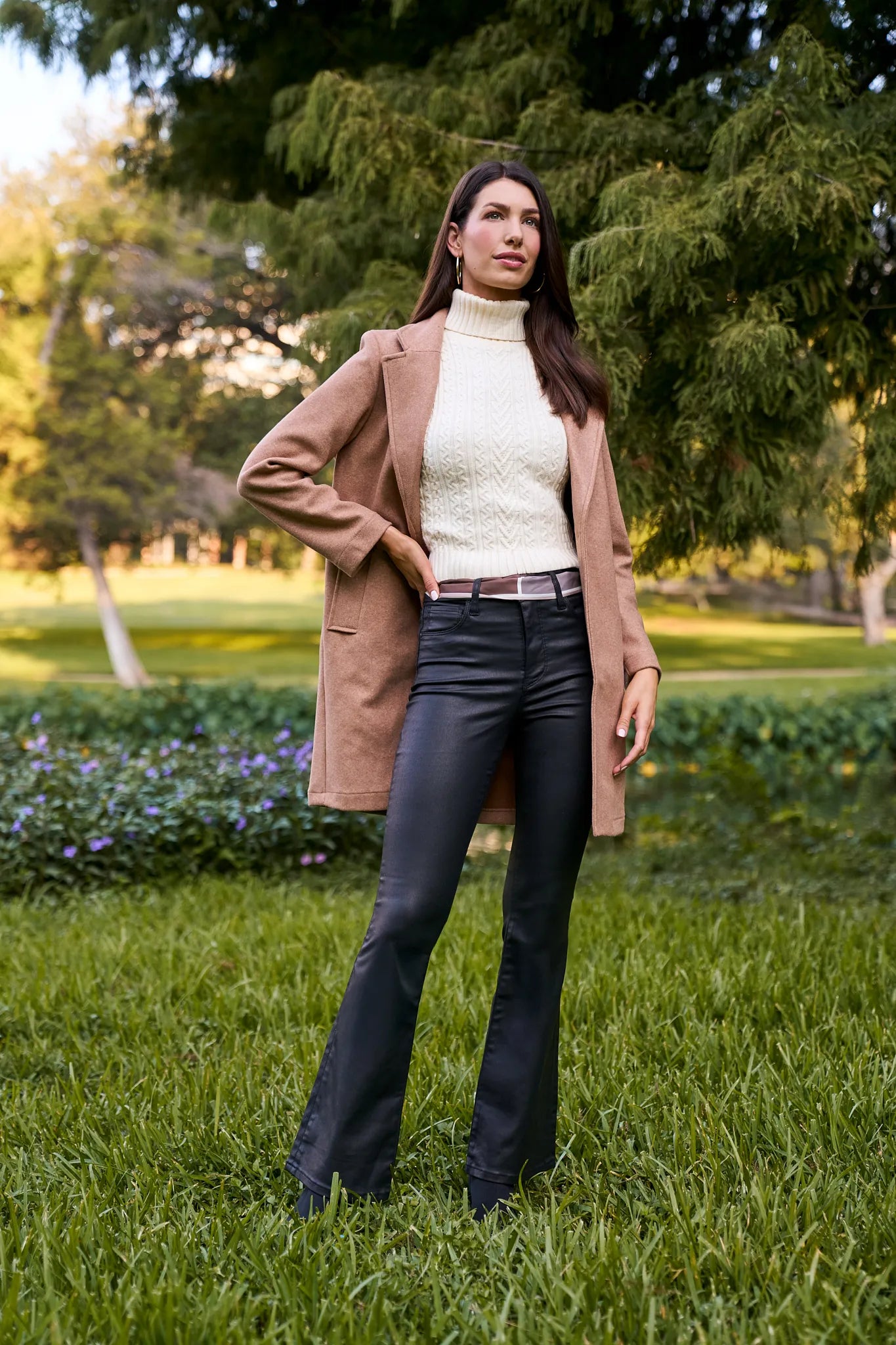 Woman in a beige coat and black Ana Jeans Wax Coated standing in a park