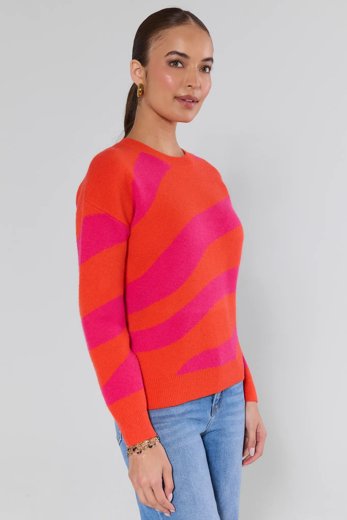 Woman wearing a red and pink striped sweater against a plain background