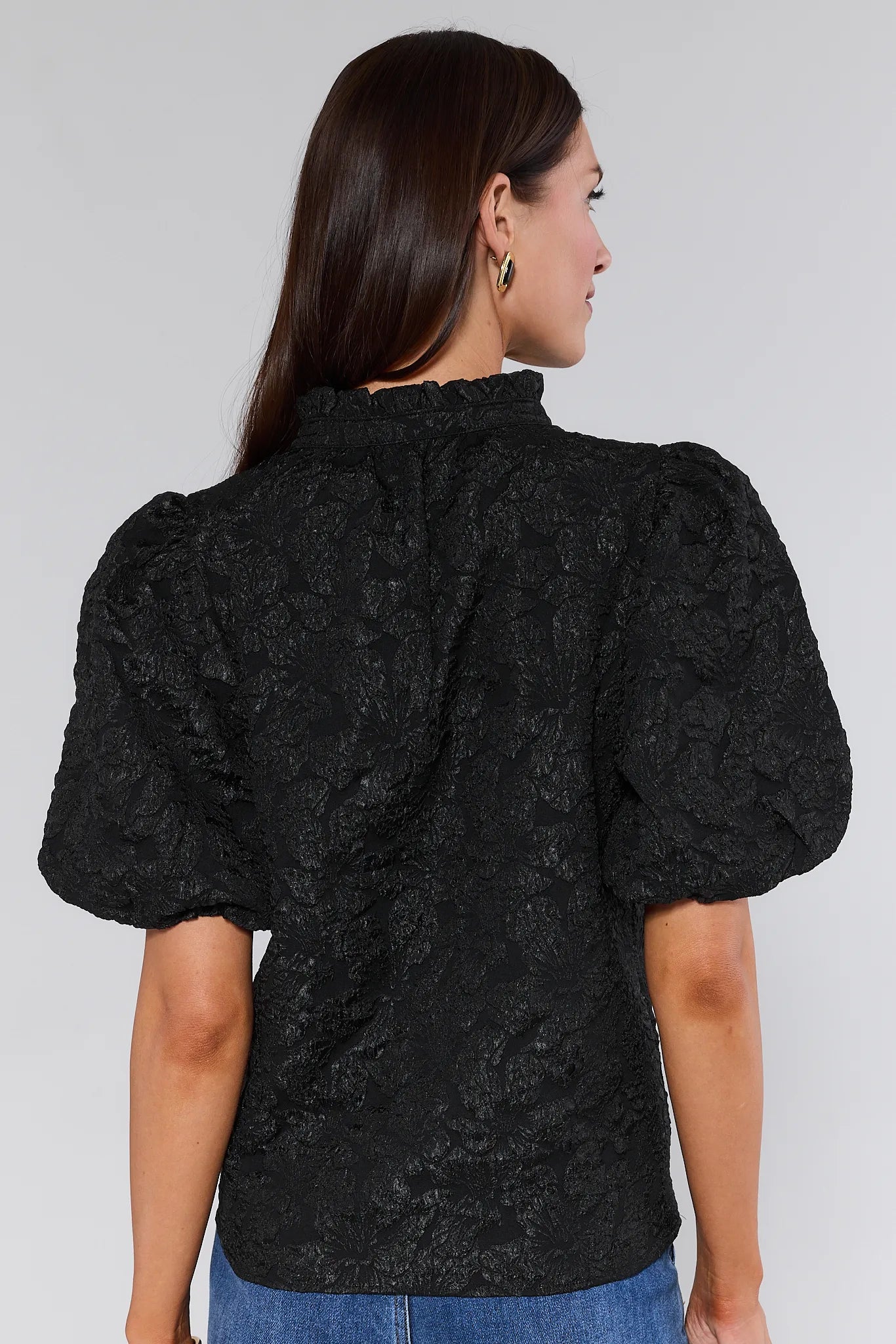 Woman wearing a Teresa Black Floral Top with puffed sleeves against a white background