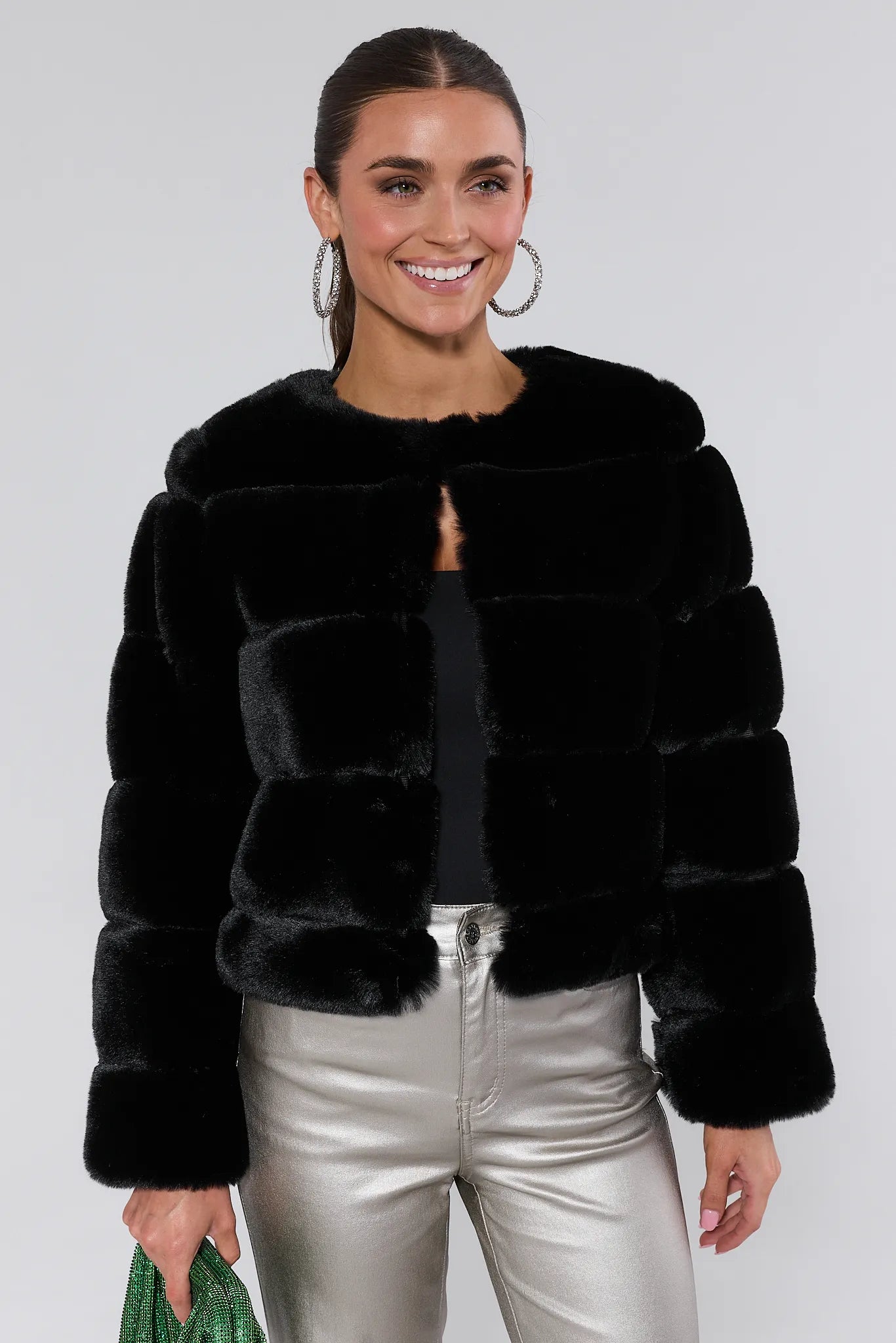 Woman wearing a Janet Black Faux Fur Jacket and silver pants on a white background