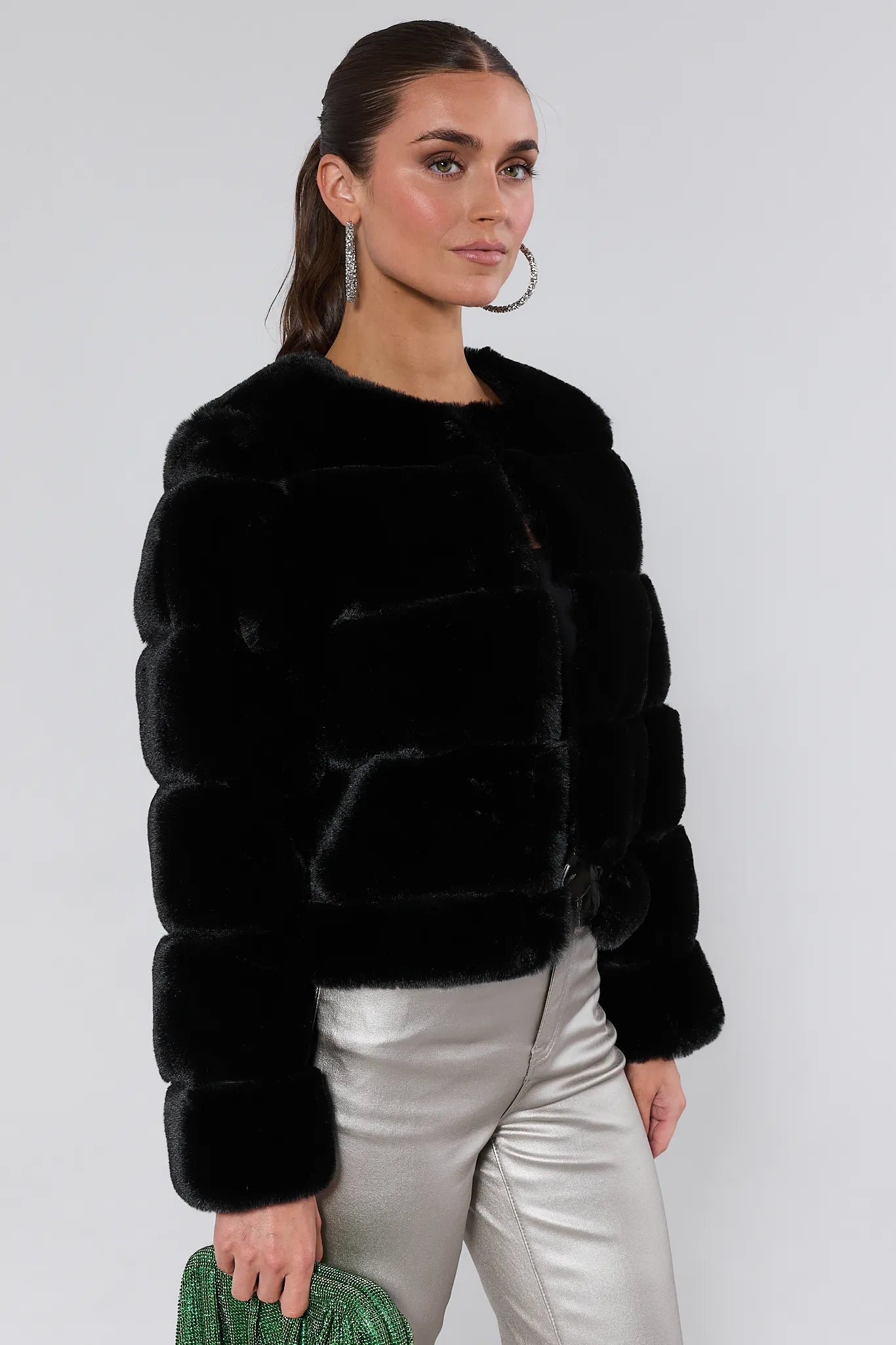 Woman wearing a Janet Black Faux Fur Jacket and silver pants on a white background