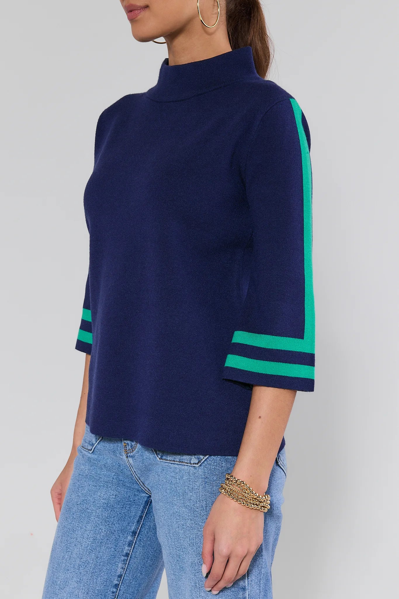Navy blue sweater with green accents worn by a person on a plain background