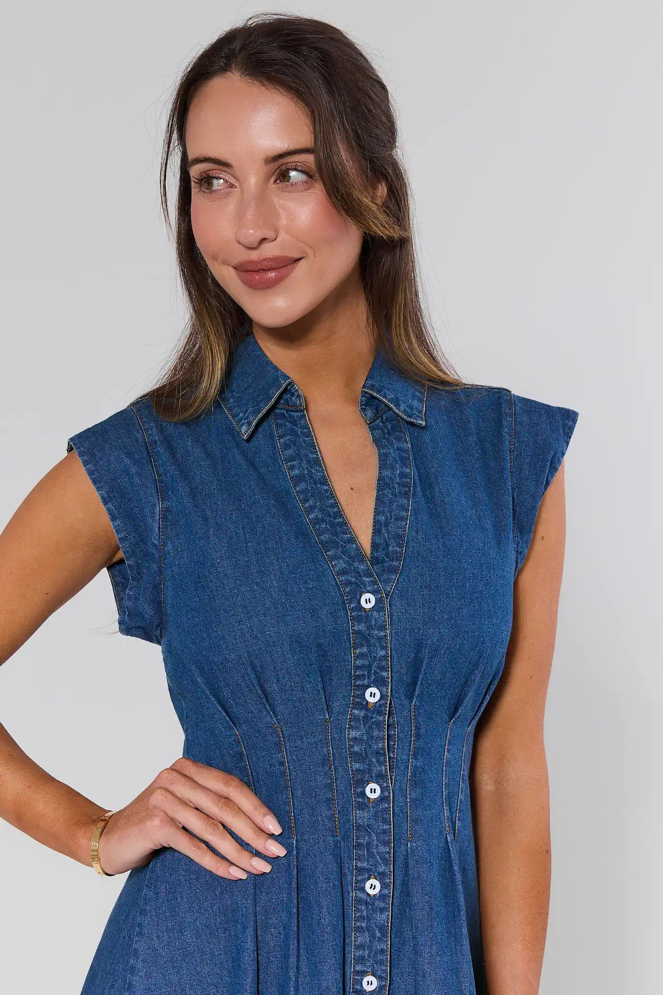 Woman wearing a blue denim dress against a plain background