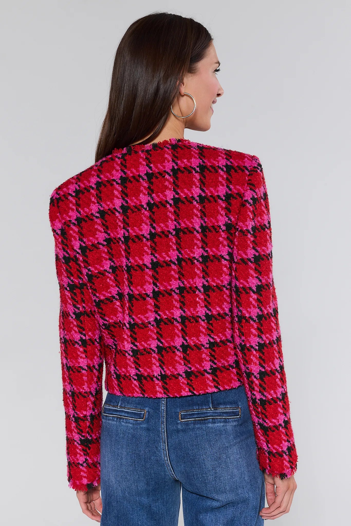Woman wearing a red and black checkered maryl jacket with blue jeans on a white background