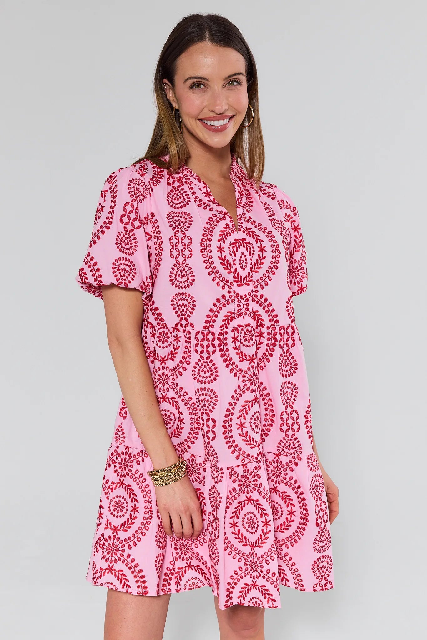 Woman wearing a pink and red patterned dress on a gray background