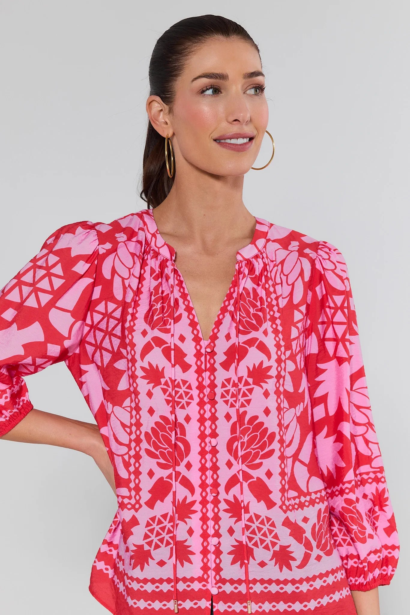 Woman wearing a pink and white patterned blouse against a gray background