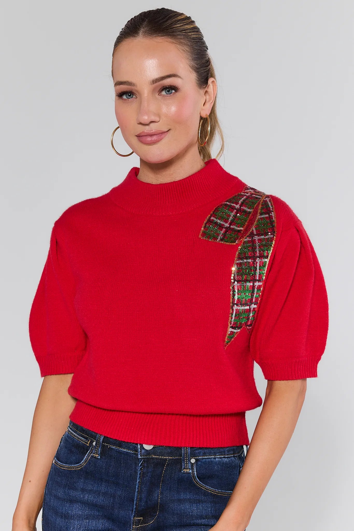 Woman wearing a Eve Red Sequin Bow Sweater on a plain background