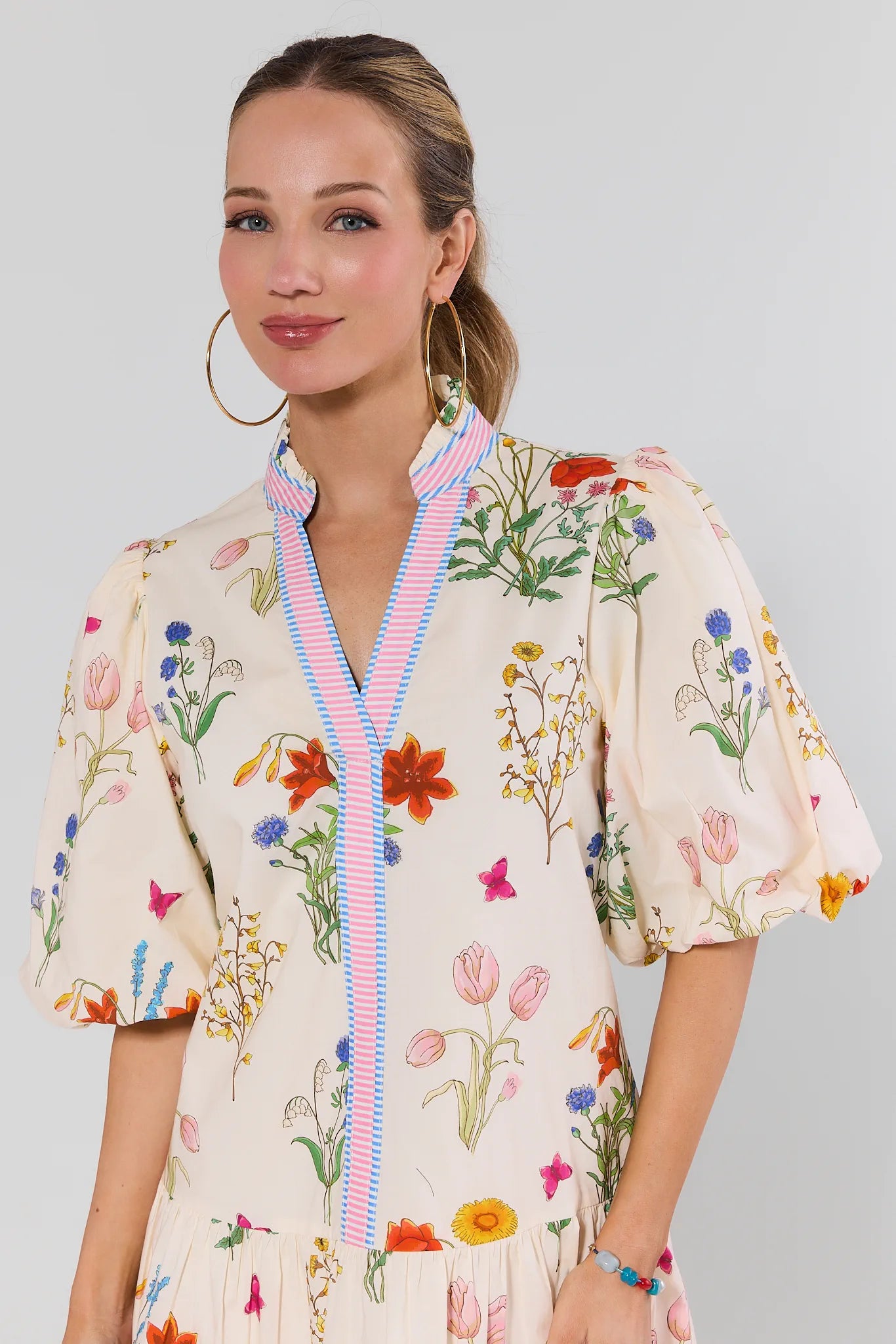 Woman wearing a floral dress with a colorful zipper on a plain background