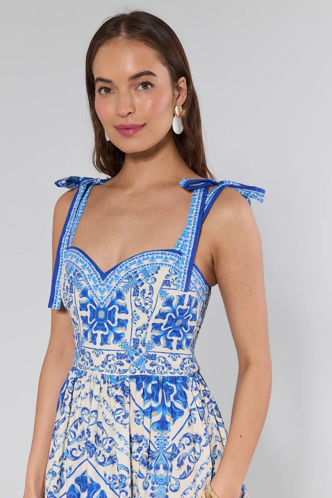 Woman wearing a blue and white patterned dress against plain background