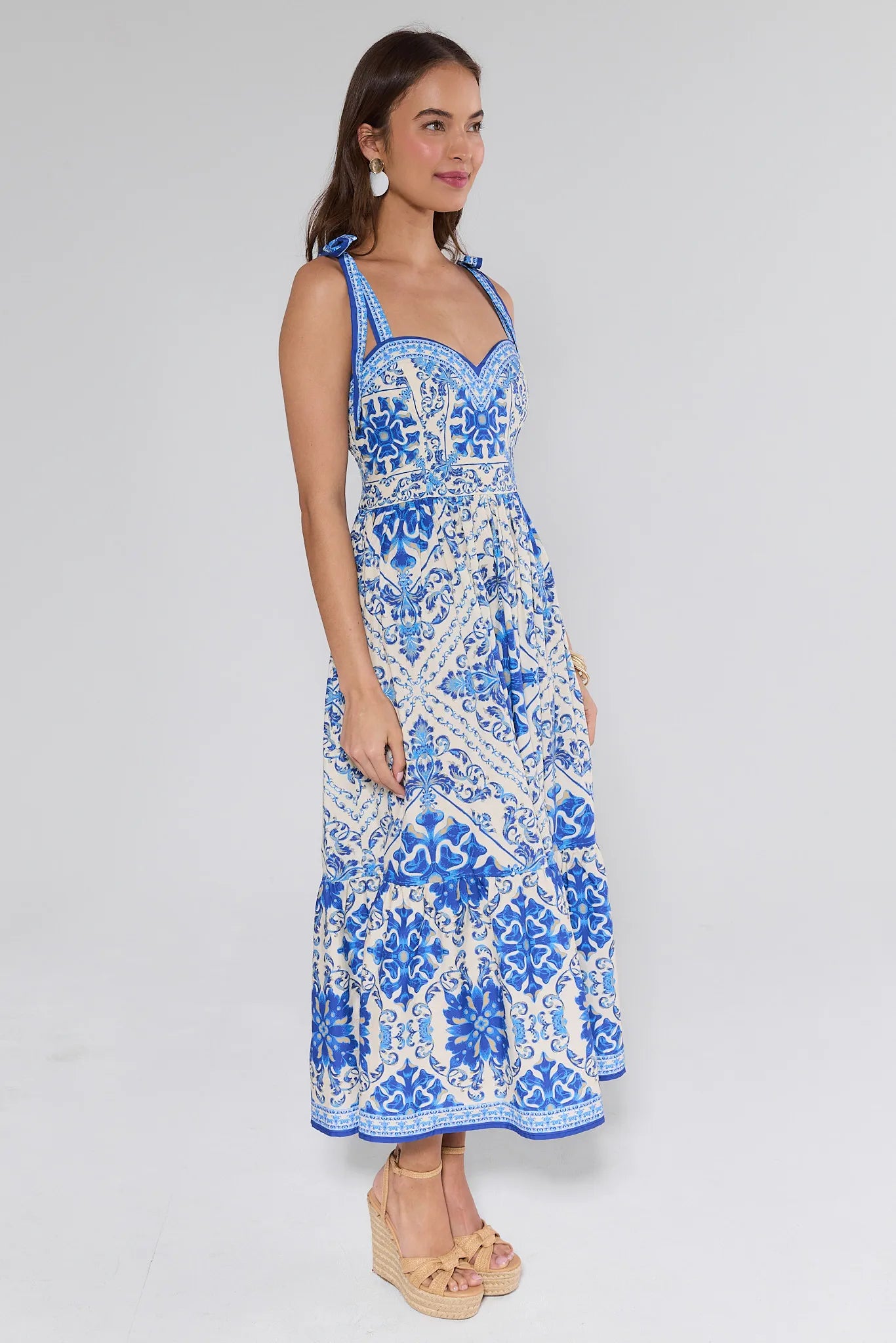 Woman wearing a blue patterned dress on a plain background